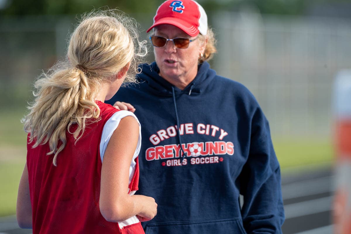 Coach Erin Blount speaking with a soccer player on the field
